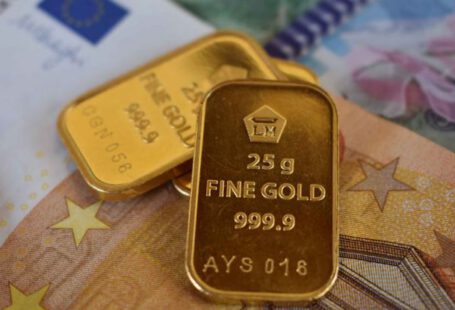 Ethical Investment - Various small pieces of gold with different currencies in the background
