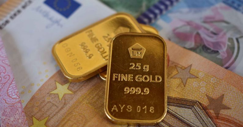 Ethical Investment - Various small pieces of gold with different currencies in the background