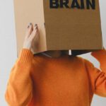 Purpose-Driven - Crop person putting Idea title in cardboard box with Brain inscription on head of female on light background