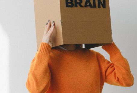 Purpose-Driven - Crop person putting Idea title in cardboard box with Brain inscription on head of female on light background