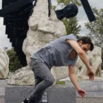Attract Talent - Young flexible man wearing casual outfit performing breakdance against modern monument Way of cross located in park of Moscow city Russian Federation